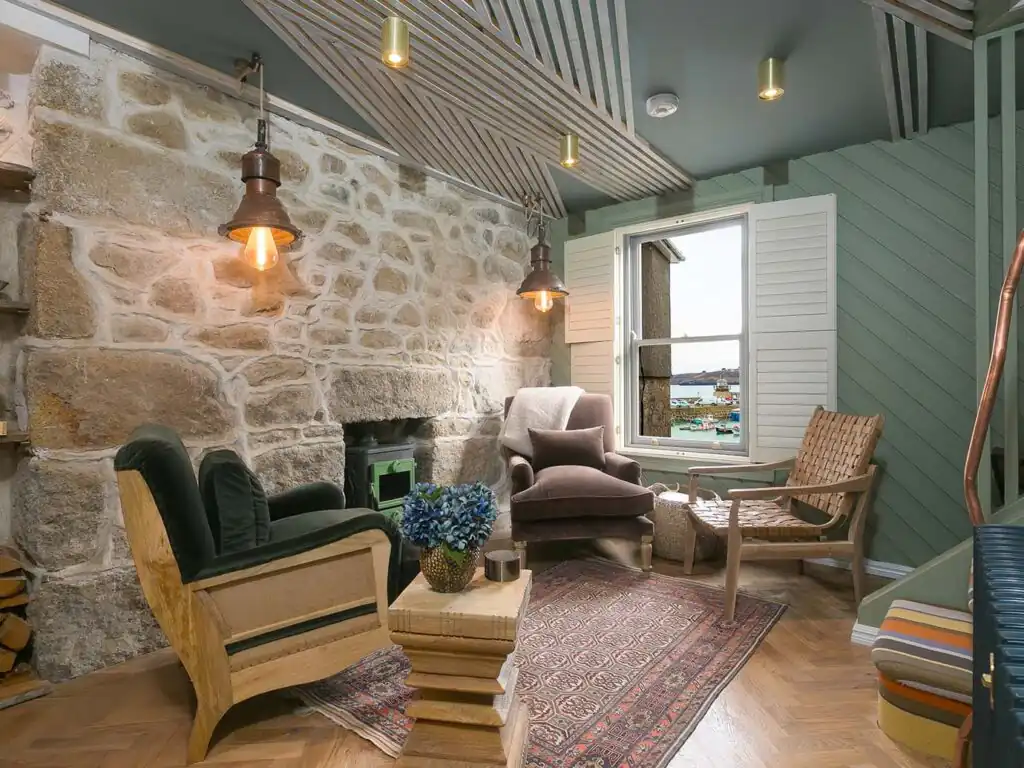 Inviting living room at She Sells Sanctuary, showcasing a charming stone fireplace and rustic wooden floor in St Ives, a great Cornwall Holiday Cottage.