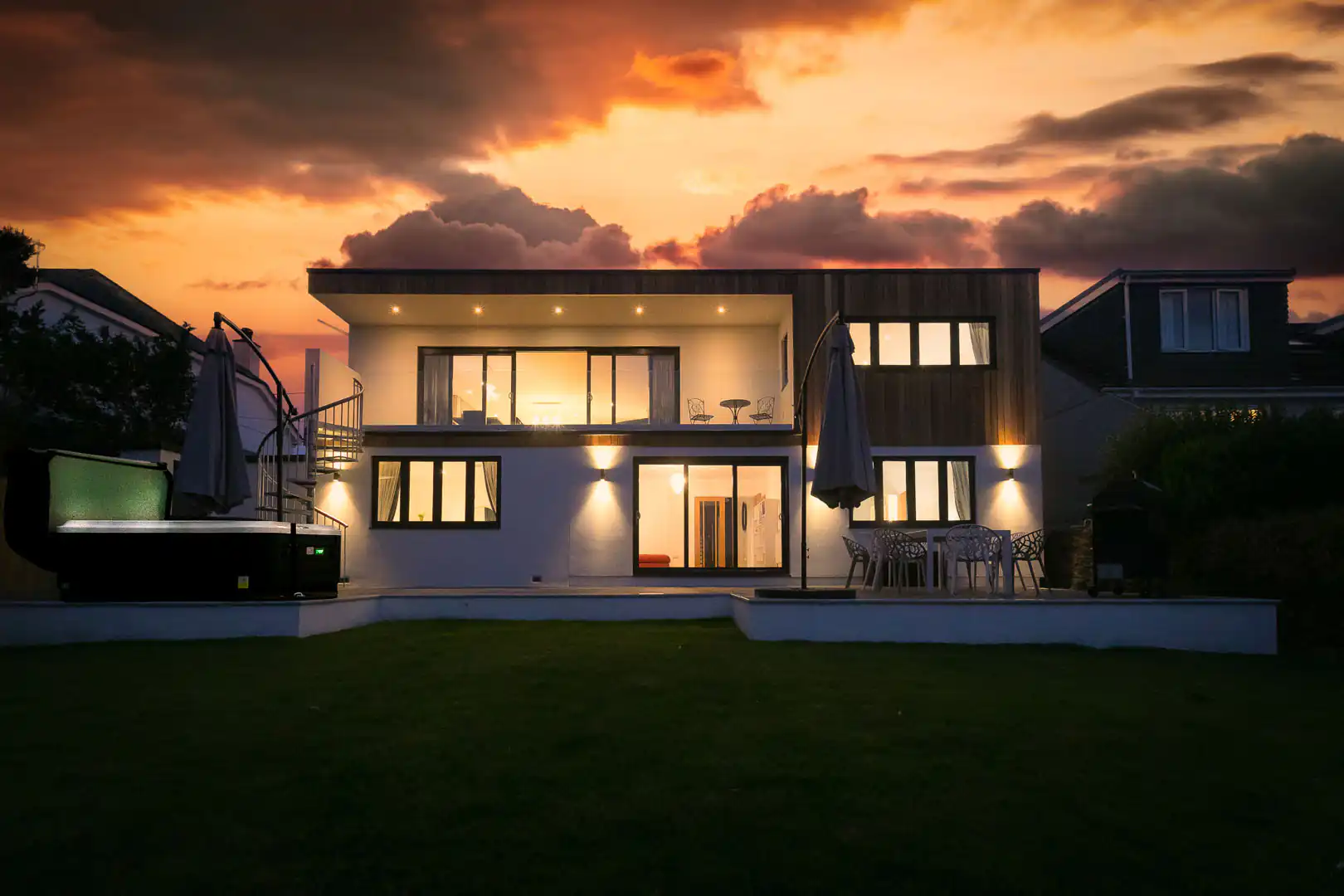 Modern holiday cottage Mor Glas in Carbis Bay, featuring a spacious deck and hot tub in a striking exterior view.
