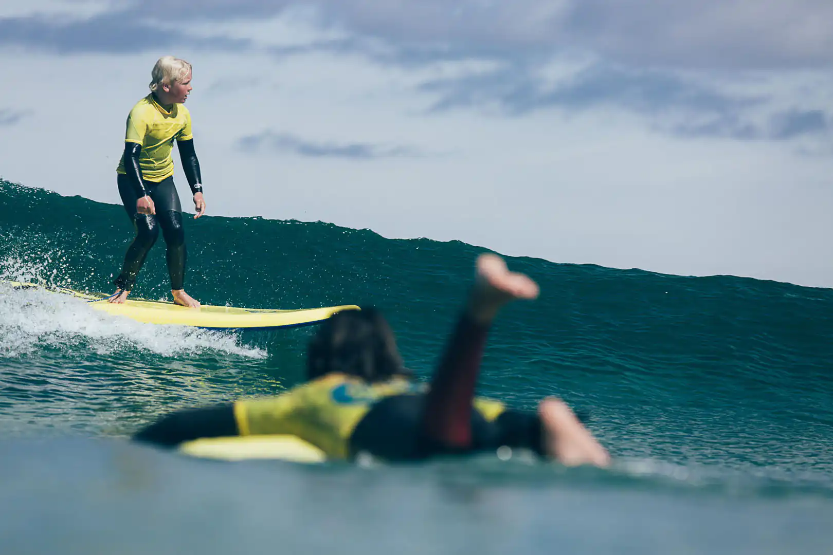 A child skilfully rides a wave on their surfboard at St Ives Surf School in West Cornwall.