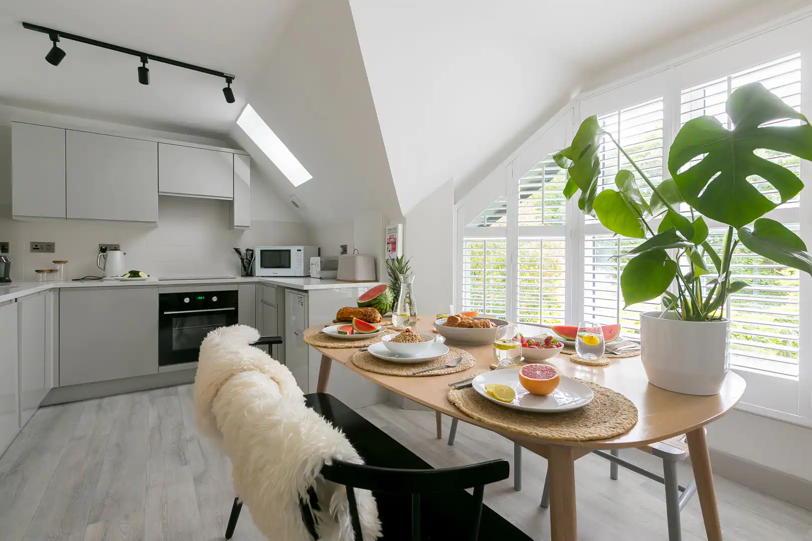 Cosy kitchen at Westholme in St Ives, featuring a table, chairs, and a vibrant plant, perfect for a holiday cottage.