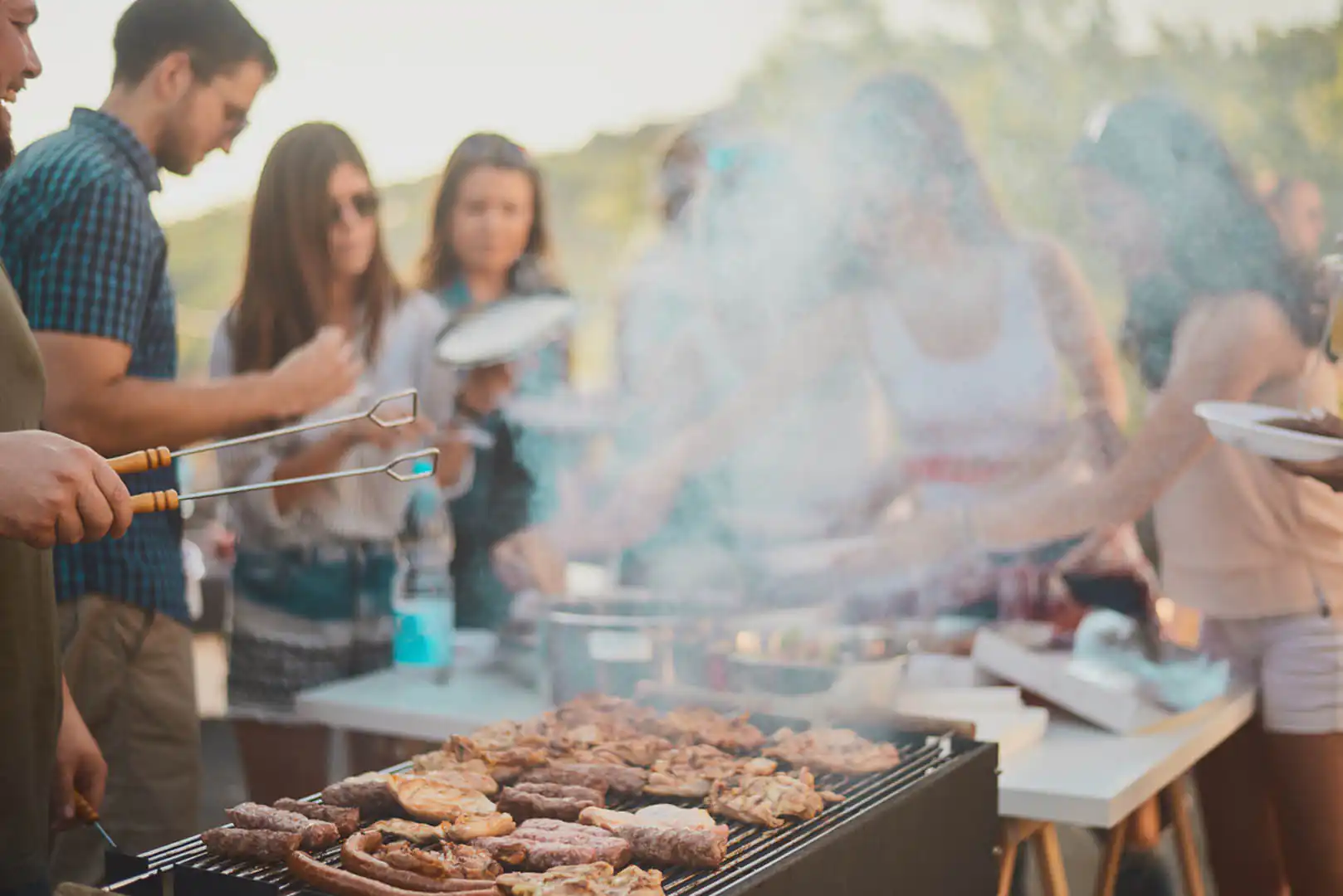 People socializing around a barbecue grill, celebrating together during a holiday for large groups in Cornwall.